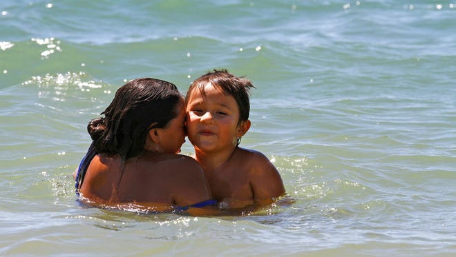Elliana Chavez and her brother, Jakie Chavez, play in the water at Farmington Lake on Monday.
