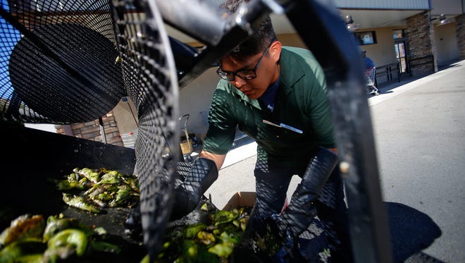 Lamuel Pinto, a produce worker at Farmers Market in Flora Vista, packs a batch of roasted green chile on Thursday.