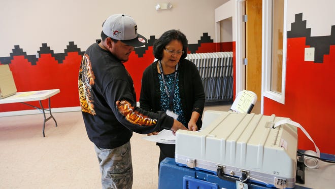 Voter Hosteen Valencia, left, is assisted by election official Renae Bennett as he casts his ballot Tuesday at the Tse Daa K'aan Chapter house in Hogback.