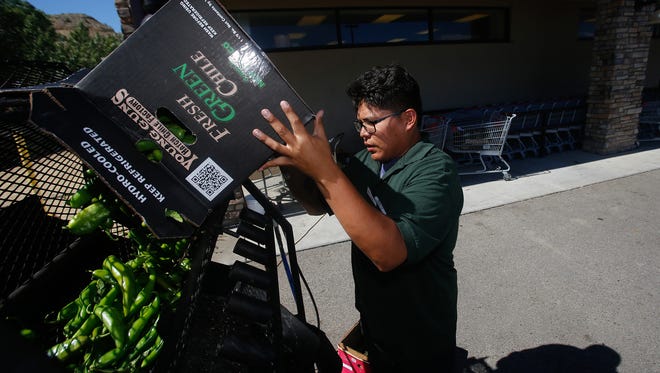Lamuel Pinto, a produce worker at Farmers Market in Flora Vista, loads a roaster with green chile on Thursday.