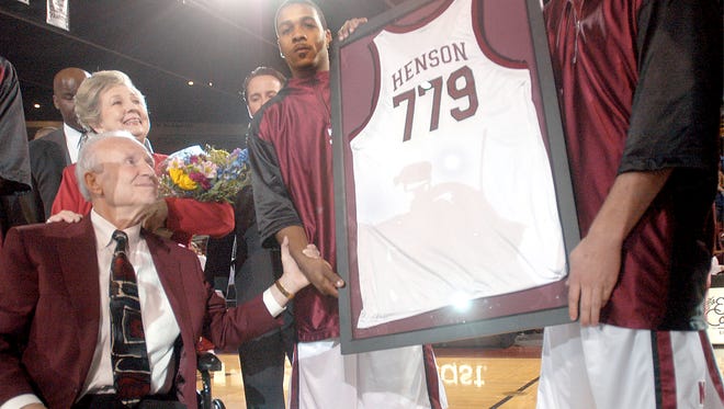 Sun-News photo by Norm Dettlaff
Former New Mexico State University men's basketball coach Lou Henson, bottom left, is awarded a game jersy Tuesday at the Pan American Center. The jersy, which has the number of Henson's career wins, is held by NMSU basketball player Allen Haynes, center, and Bryant Funston. Standing behind him is his wife Mary.