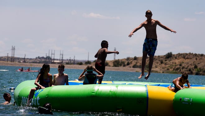A group of swimmers play on an inflatable structure, Monday, July 3, 2017 at Farmington Lake.
