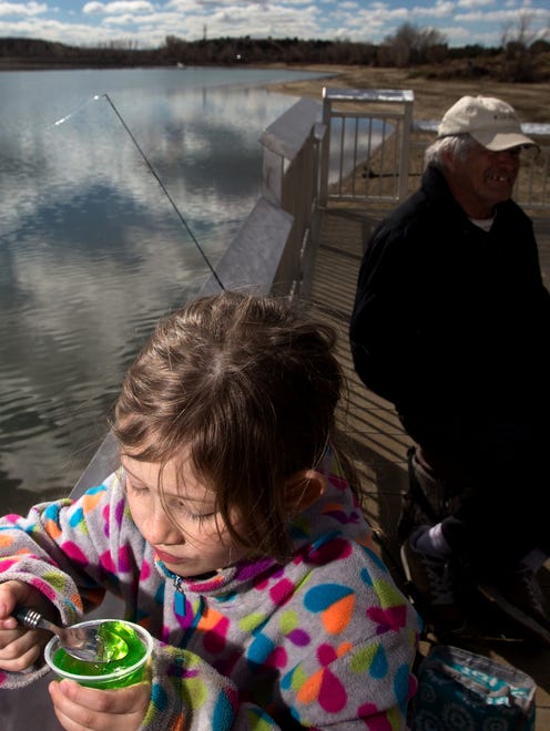 Elizabeth Howerton enjoys a snack while fishing with her grandfather Curtis Howerton, on Monday at Farmington Lake.