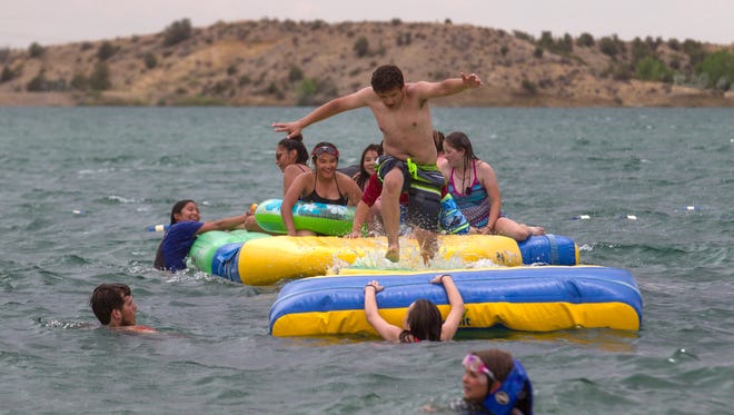 Swimmers play on inflatable structures, Thursday, April 14, 2018 at Farmington Lake.