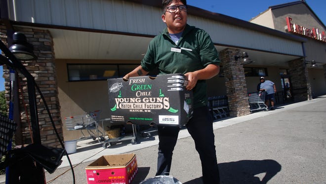 Lamuel Pinto, a produce worker at Farmers Market, carries a batch of green chile to a customer on Thursday at the grocery story in Flora Vista.
