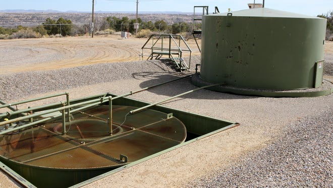 A below-grade tank, front, that stores water from the oil tank, back, and three-phase separator, not pictured, as seen Friday March 11, 2016, at an XTO Energy natural gas well facility near Piedra Vista High School.