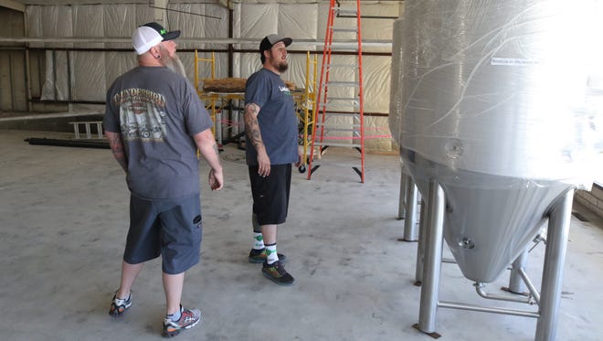 Brad Foley, left, and Brandon Beard examine the fermenters that were delivered recently to the soon-to-open Lauter Haus Brewing Company in Farmington.