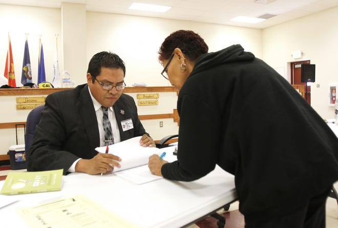 Poll worker Jamie Joe helps voter Irene Mason receive her ballot during the Nov. 4, 2014, general election at the Upper Fruitland Chapter house in Upper Fruitland.