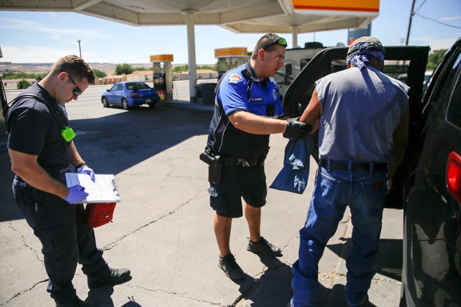 Farmington Fire Department Station One Capt. Mike Stahll and Farmington Police Department District Coordinator Ofc. Kris Chavez prepare to transport an inebriated person to the Sobering Center, Thursday, Aug. 30, 2018 shortly after making contact with the individual at the Shell gas station off West Apache Street in Farmington.