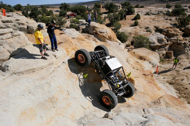 Randall Davis, second from the left, guides driver Cody Waggoner, both from Dana Point, California, up a rock face, Saturday, Sept. 8, 2018 during the W.E. Rock Grand Nationals at the Brown Spring Campground rock crawl in Glade Run north of Farmington.