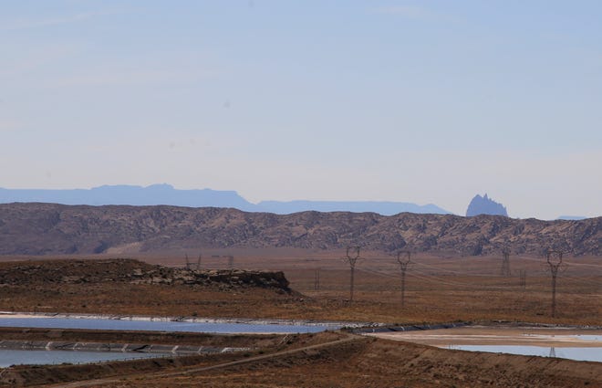 The Shiprock pinnacle can be seen, Wednesday, Sept. 25, 2019, from the San Juan Generating Station. Meanwhile, transmission lines transport electricity away from the power plant.
