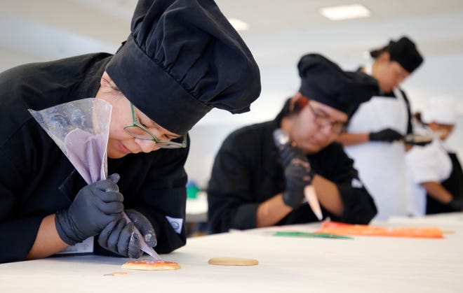 Miyamura High School student Tiger Lillie Castillo, left, decorates a cookie during the baking competition at Skills Fest on Oct. 22 at Navajo Technical University in Crownpoint.
