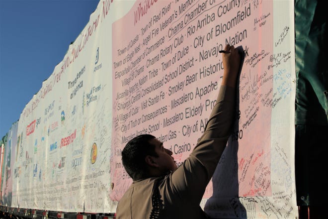 An attendee to the event to welcome the U.S. Capitol Christmas tree to Shiprock High School signs his name on a banner covering the tree on Nov. 13, 2019.