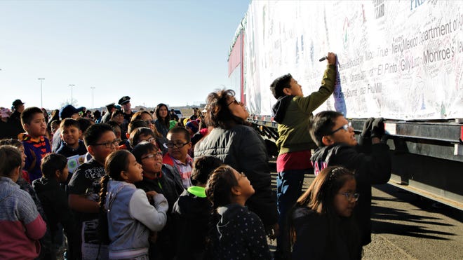 Students from Atsá Biyáázh Community School sign the canvas covering the U.S. Capitol Christmas tree in the parking lot of Shiprock High School in Shiprock on Nov. 13, 2019.