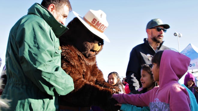 A first grade student from Atsá Biyáázh Community School meets Smokey Bear at an event to welcome the U.S. Capitol Christmas tree to Shiprock High School in Shiprock on Nov. 13, 2019.