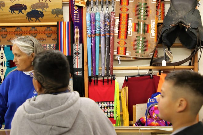 Cashier at Alex Benally's Hogan Eletta Zmudzinski helps customers Ethan Begay, left, and Jerimiah Tracy, right, look for gifts on Nov. 30, 2019, Small Business Saturday in Farmington.