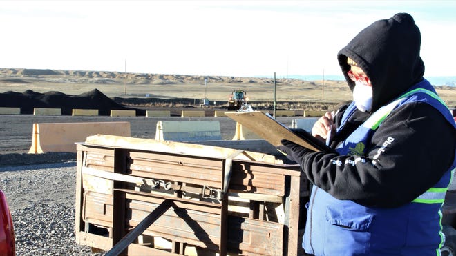 Security Guard for Dinéland Protection Services, Kristy Dempsey, checks tickets and license plates of Navajo Nation members lined up to receive their free allotment of coal for home heating at Navajo Mine in Fruitland on Feb. 6, 2020.