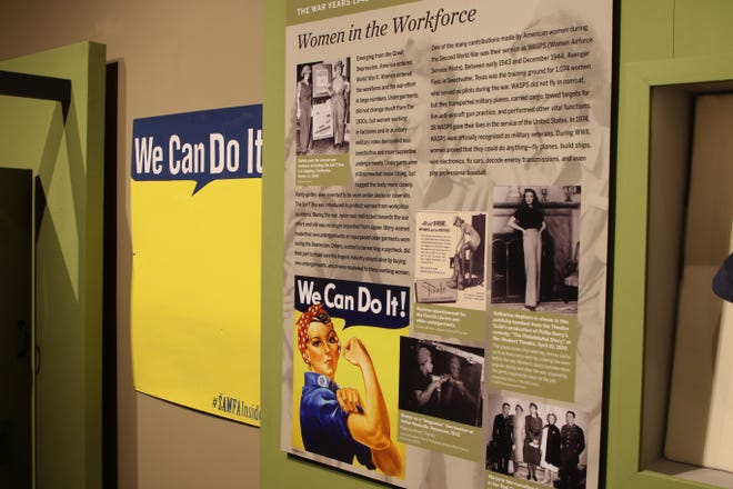 A display on working women during the World War II era features a selfie station, left, where visitors can take a photo against a Rosie the Riveter-type background.