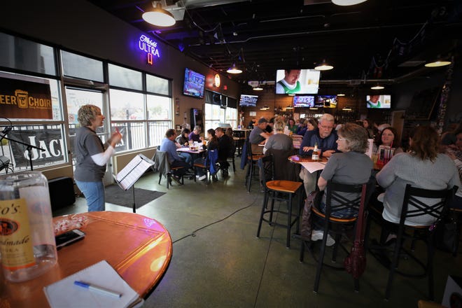 Virginia Nickels-Hircock, left, leads the crowd in a song during the Beer Choir gathering on March 11 at Traegers bar in Farmington.