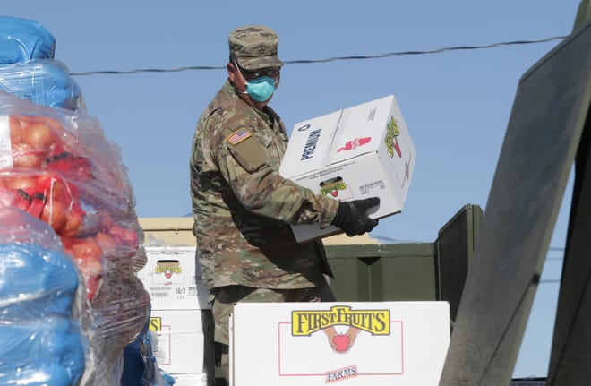 New Mexico Army National Guard member Pfc. Edwin Rodriguez carries a box of apples as part of a donation by the State of New Mexico to the Navajo Nation on April 15, 2020 in Sheep Springs.