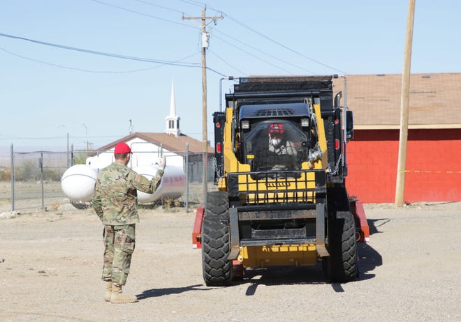 New Mexico Air National Guard member Tech. Sgt. Wesley Grassie, left, directs Senior Airman Micah Thompson as he controls a forklift on April 15, 2020 in Sheep Springs.