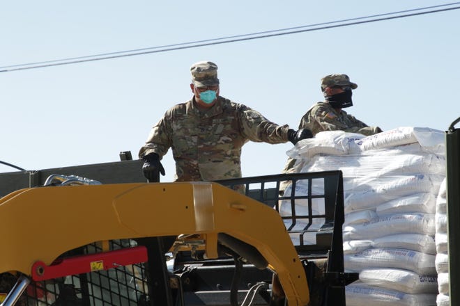 From left, New Mexico Army National Guard members Pfc. Edwin Rodriguez and Staff Sgt. Wayland Green help remove pinto beans donated to the Navajo Nation by the State of New Mexico on April 15, 2020 in Sheep Springs.