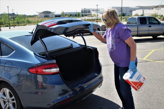 San Juan College English professor Danielle Sullivan retrieves a package of paper towels from the trunk of a car May 8 on the college campus during a donation drive for people on the Navajo Nation who are struggling because of the COVID-19 shutdown.