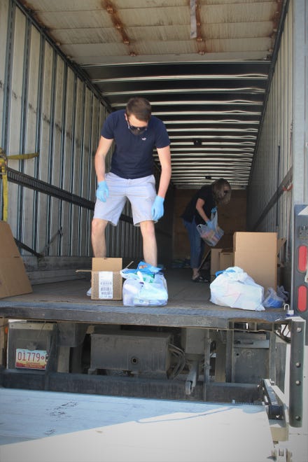 Volunteers Ethan Sullivan and San Juan College professor Sherri Cummins move goods to the front of a semi-trailer on May 8 on the college campus during a donation drive for people on the Navajo Nation impacted by the COVID-19 shutdown.