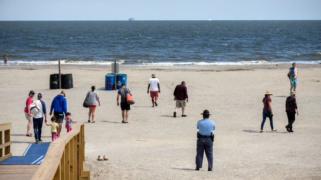 Georgia State Patrol Capt. Thornell King, bottom right, watches visitors to Tybee Island, Ga. Restrictions on Tybee Island were lifted on May 6, allowing visitors and for vacation rentals to continue. The beach town is known for its colorful cottages and family attractions.