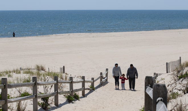 A family walks up the dune walkway to leading off the beach in Surf City, NJ, on Long Beach Island on May 14, 2020. Long Beach Island is an 18-mile barrier island, offering summer renters access to the ocean. The Jersey Shore will reopen for Memorial Day weekend, but some restrictions will be set in place.