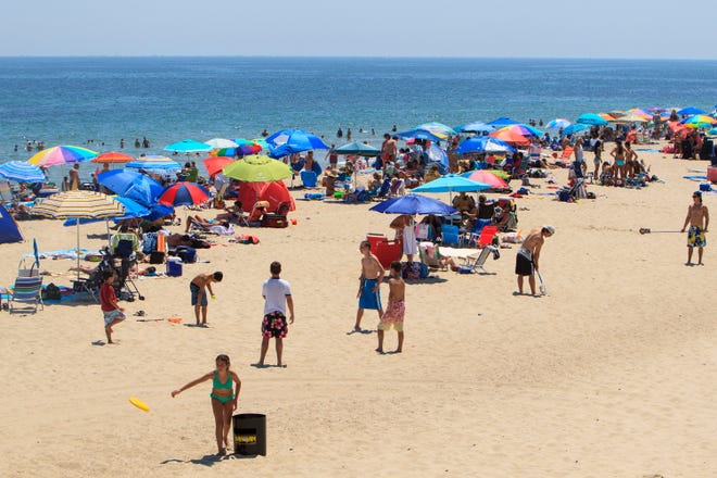 This file image of Nauset Beach in Orleans, Mass. shows umbrellas and sunbathers on July 28, 2017. This popular tourist beach is currently open, allowing day-trippers and vacationers to visit.