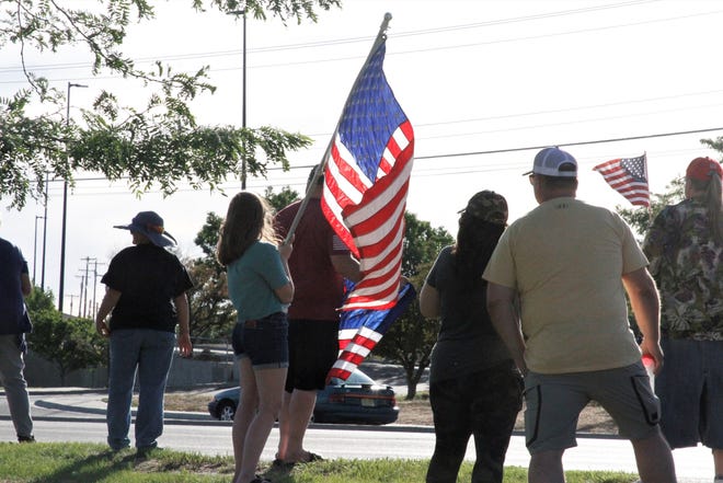 Demonstrators carry American flags, Friday, June 19, 2020, during a rally in support of law enforcement in front of Animas Valley Mall in Farmington.