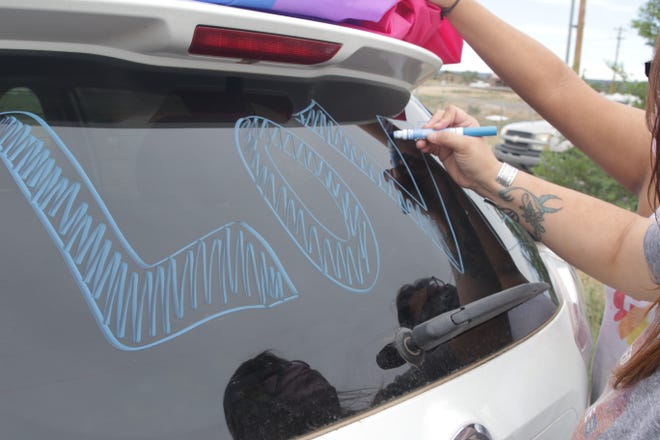 Krystle Headley writes the word "love" on the back window of her vehicle prior to the start of the Diné Pride Cruise on June 26 in Window Rock, Arizona.