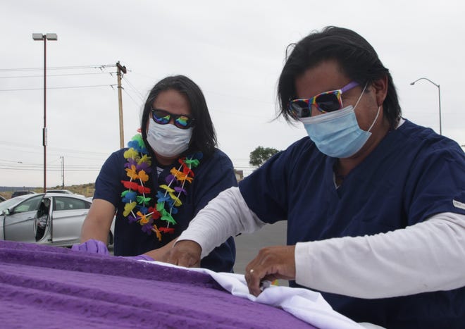 Jody Lynch, left, and Ty Ra use fabric to decorate a truck before the Diné Pride Cruise on June 26 in Window Rock, Arizona.