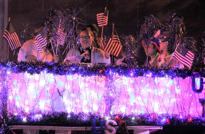 Riders on a float wave to the crowd during the 2019 Electric Light Parade in downtown Farmington.