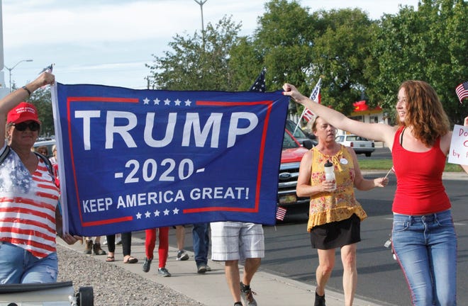 Christy Grossheim and Ray Hill carry a banner supporting President Donald Trump, Saturday, July 11, 2020, during the Freedom March in Farmington.