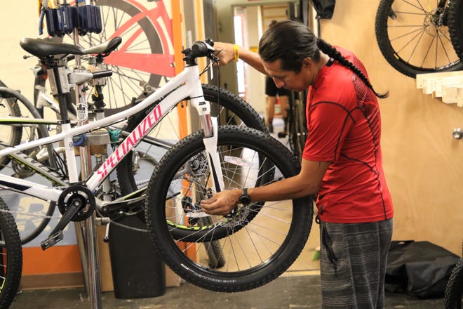 Bisti Bicycles bike technician Shane Rakestraw checks the front tire of a bike on Monday, July 13, 2020, in Farmington.