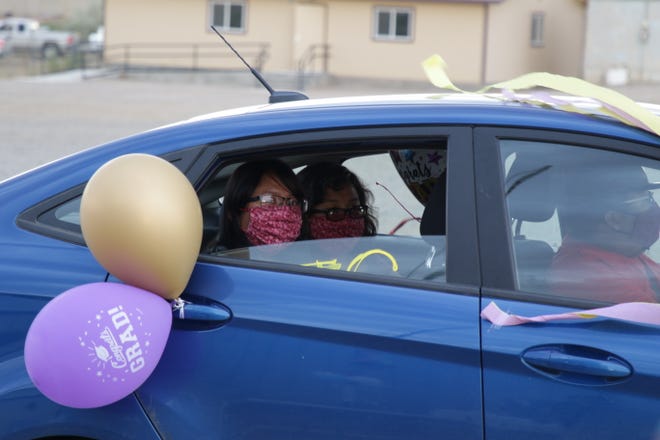 A pair of college graduates from Sanostee drive by the Tsé Alnaozt'i'í Chapter area after participating in a parade on July 17 to recognize their graduations. Chapter officials and members of the chapter's emergency response team organized to celebrate students from the community.