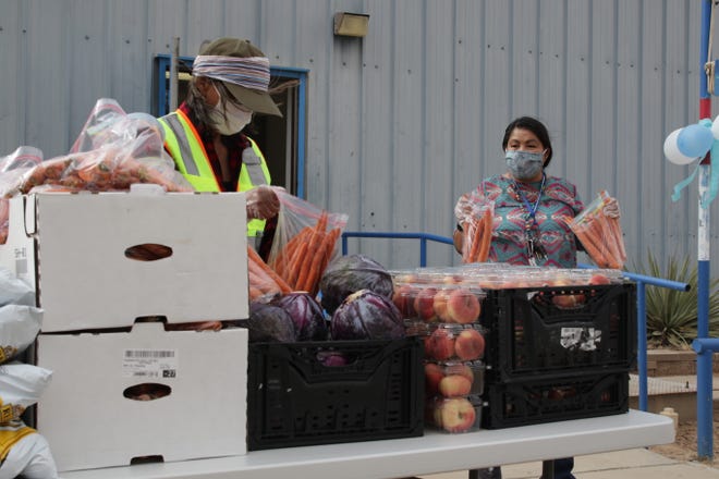 At left, Mae Mallahan, community service coordinator with Tsé Alnaozt'i'í Chapter, and Shelia Mitchell, account maintenance for Tsé Alnaozt'i'í Chapter, sort vegetables to give to graduates during a non-contact event on July 17 to recognize graduates in Sanostee.