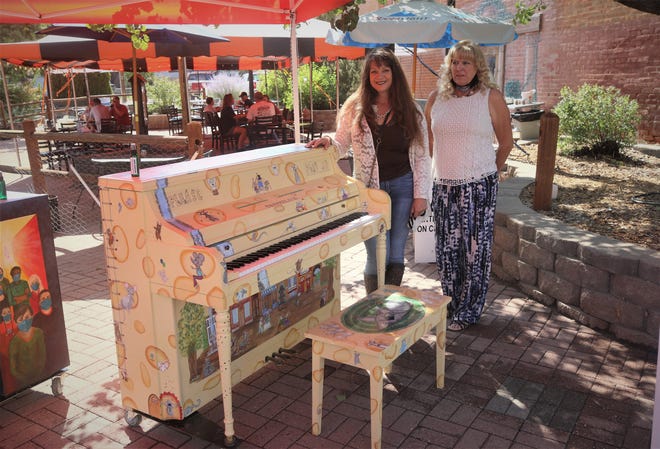 Artists Cindy Iacovetto, left, and Connie Hutcheson display their piano painted in a Swiss cheese-and-mice theme on Aug. 15, 2020, at the Main Avenue Plaza in Aztec.