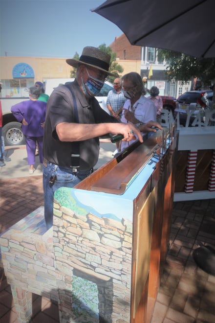 Artist Timithy Gordon, left, talks with musician Hoyle Osborne on Aug. 15, 2020, in the Main Avenue Plaza in downtown Aztec as he sanitizes his piano painted in an Aztec Ruins National Monument theme.