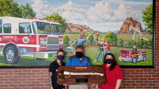 From left to right: Assistant Manager Taylor Dewees, Franchisee Darin Fitzgerald and General Manager Charity Morales showcasing the Axe Award in front of Firehouse Subs Farmington’s mural.