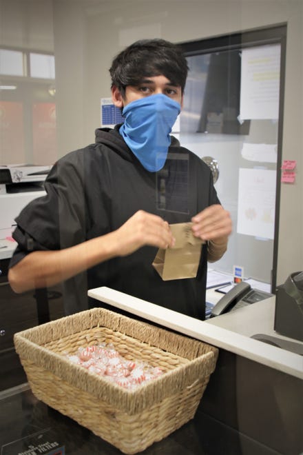 Cashier Nathan Gonzales rings up a purchase on Nov. 12, 2020, at Farmington's New Mexico Alternative Care.