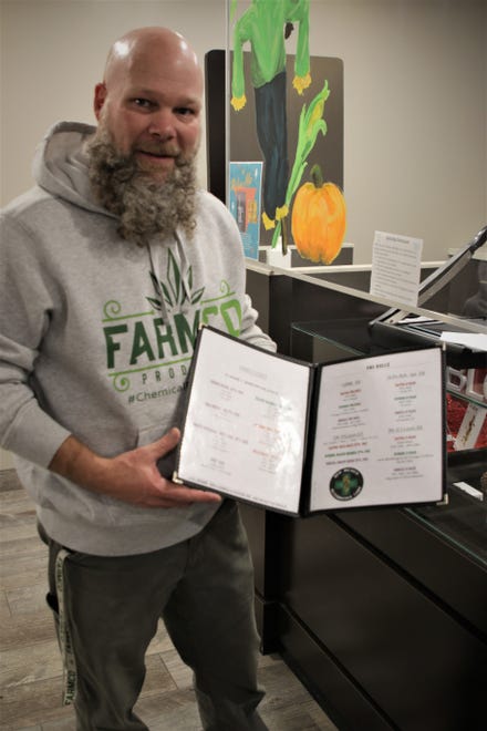 Owner Jason Little displays a menu of the offerings at New Mexico Alternative Care in Farmington on Nov. 12, 2020.