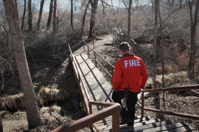 Battalion Chief Tom Miller of the Farmington Fire Department prepares to cross a bridge over a drainage in Berg Park on March 2, 2021, while leading a walk-through of the area, which is having overgrown brush thinned and invasive tree species removed.
