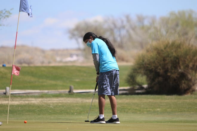 Navajo Prep’s Kyle Begay sinks his ball putting on the ninth green during the Aztec Invitational on Monday, April 19, 2021, at Riverview Golf Course in Kirtland.