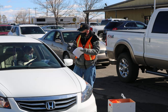 Drivers check in with a volunteer before receiving a COVID-19 vaccination on Jan. 30, 2021, during a drive-thru clinic at McGee Park outside Farmington.