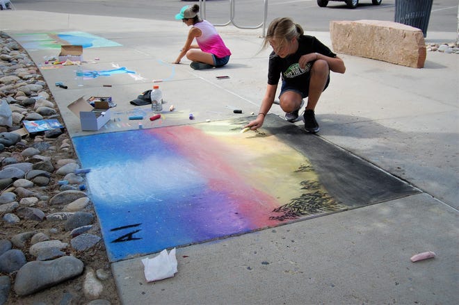 Abbigail Jaramillo, front, and Lilly Yocum work on their entries for the Chalk Art Festival outside the Farmington Public Library on June 10.