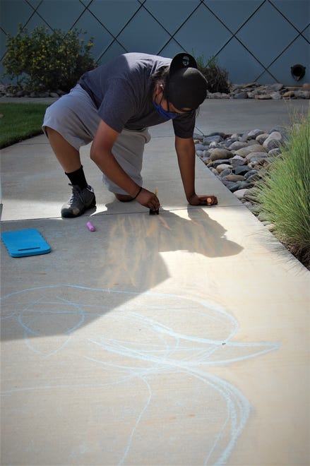 Zane Lee uses a paint brush to smooth out his entry in the Farmington Public Library's Chalk Art Festival on June 10.