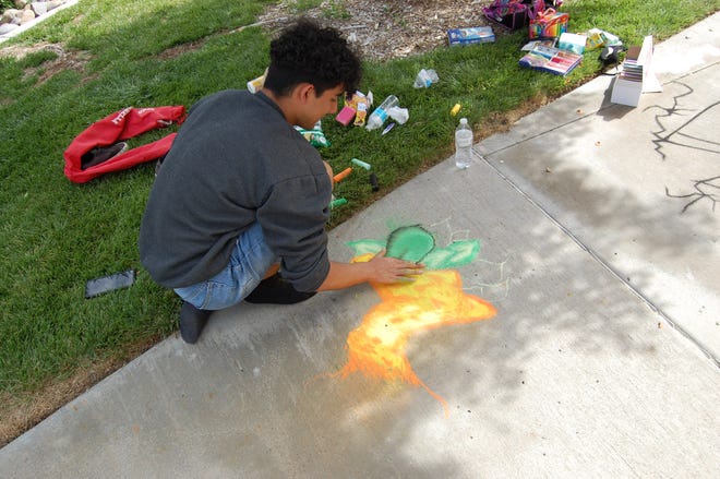 Kalib Robles uses his fingertips to smooth a detail in his entry in the Farmington Public Library's Chalk Art Festival on June 10